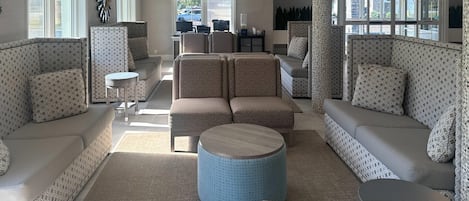 A modern hotel lobby with patterned sofas, a central round table, and a reception desk.
