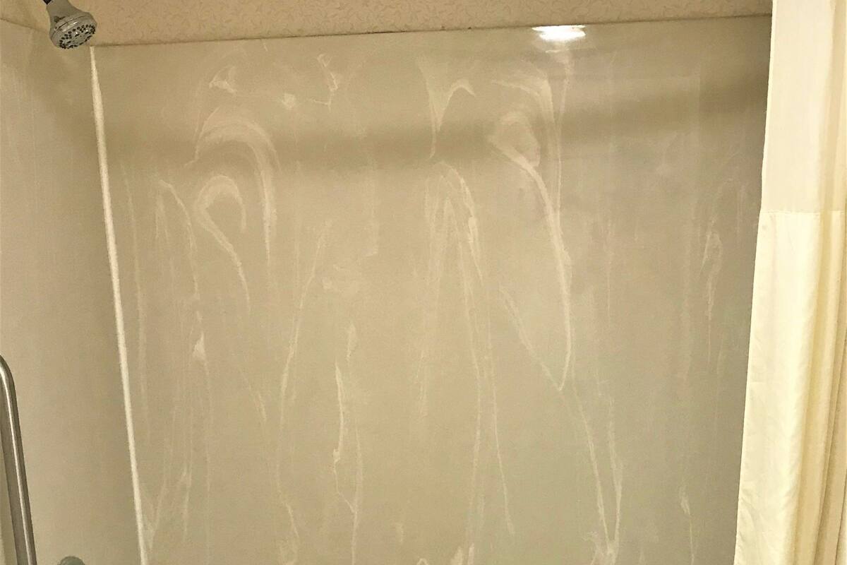 A bathroom with a bathtub, a showerhead, and a curtain.