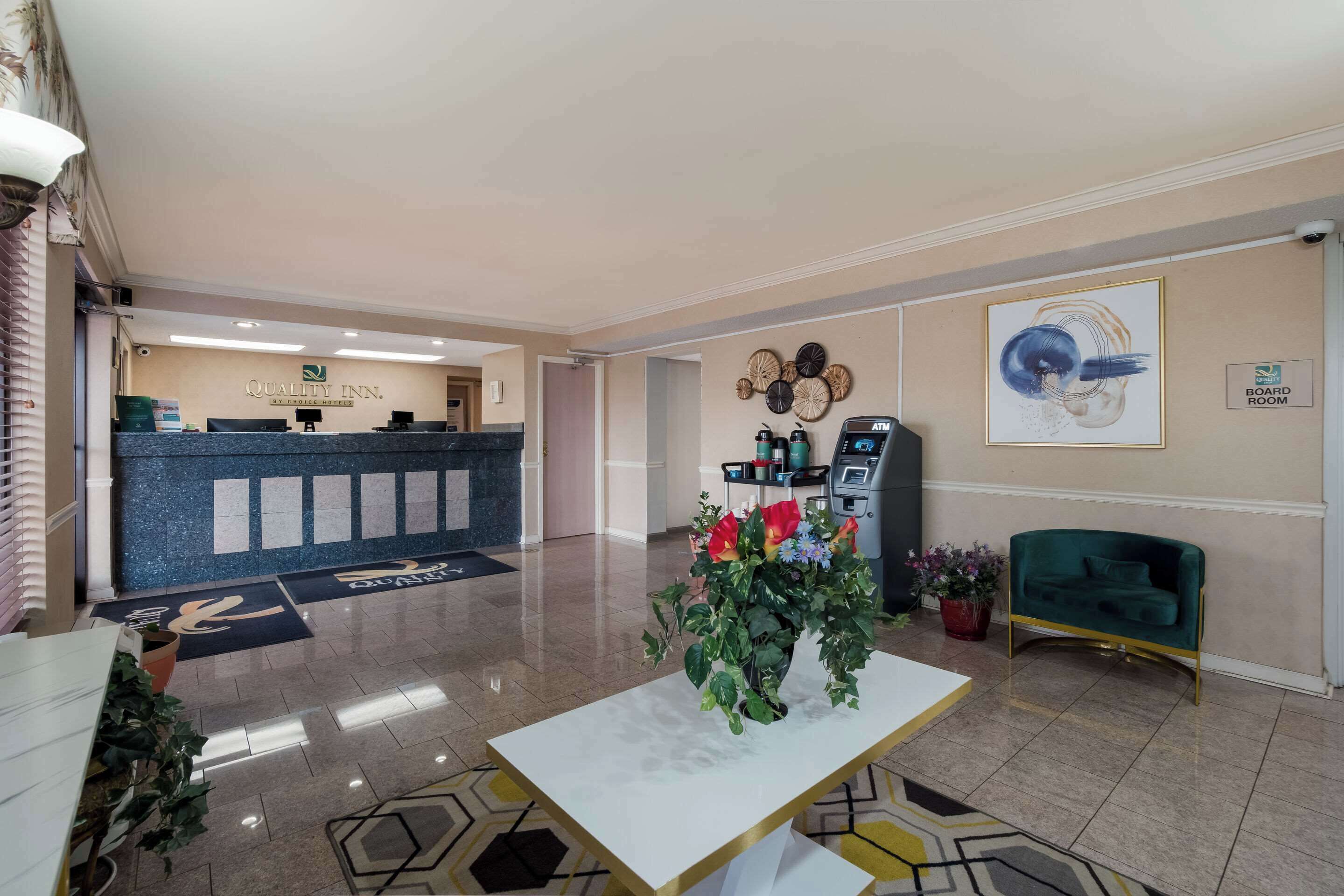 A hotel lobby with a reception desk, ATM, and a board room sign.