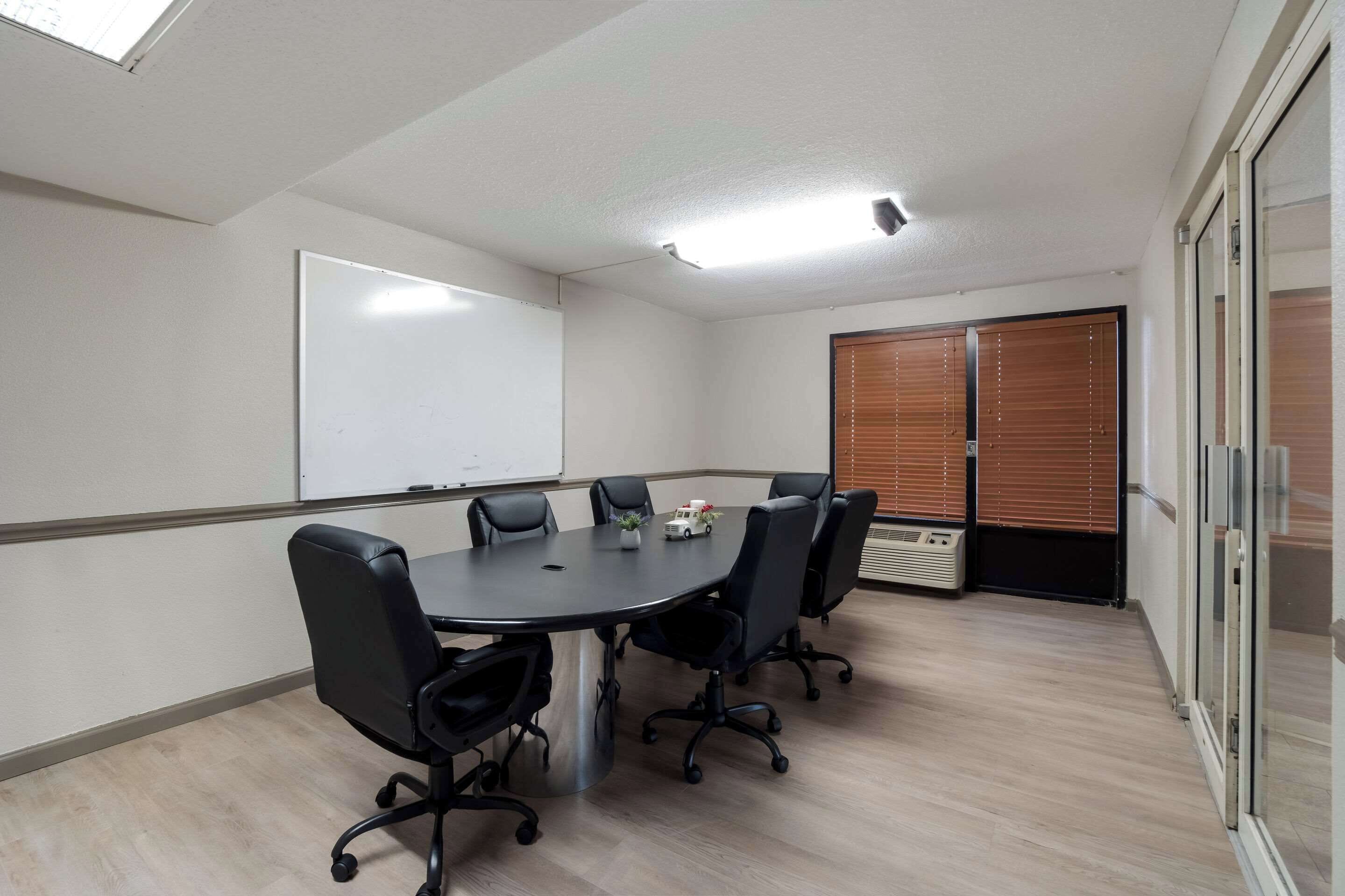 A conference room with a whiteboard, a round table, and six chairs.