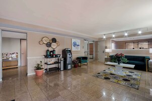A spacious lobby with a reception desk, self-service kiosk, and a green sofa.