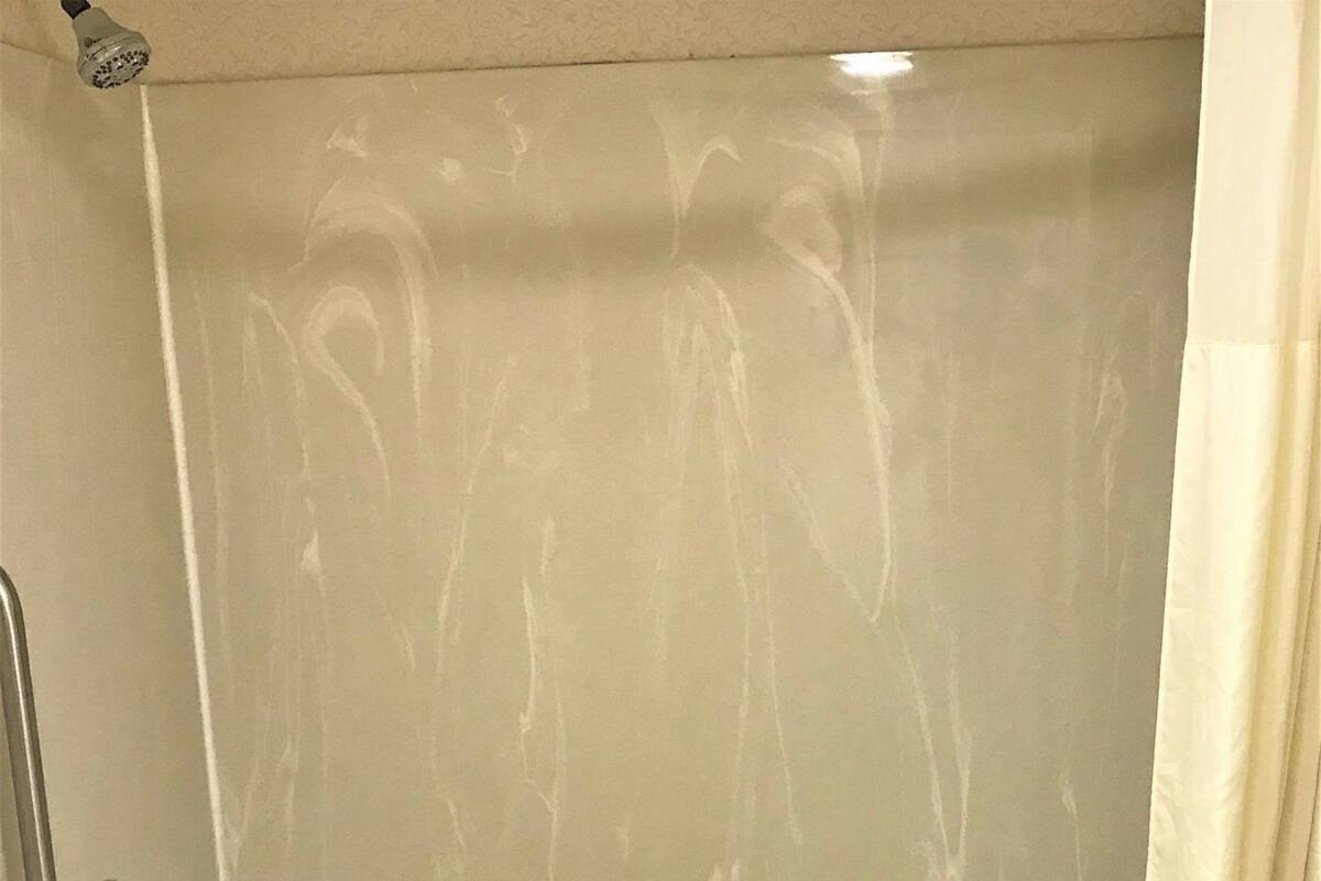 A bathtub with a showerhead, a grab bar, and a towel.