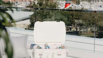 A white cooler with bottles on a balcony overlooking a marina with boats and houses.