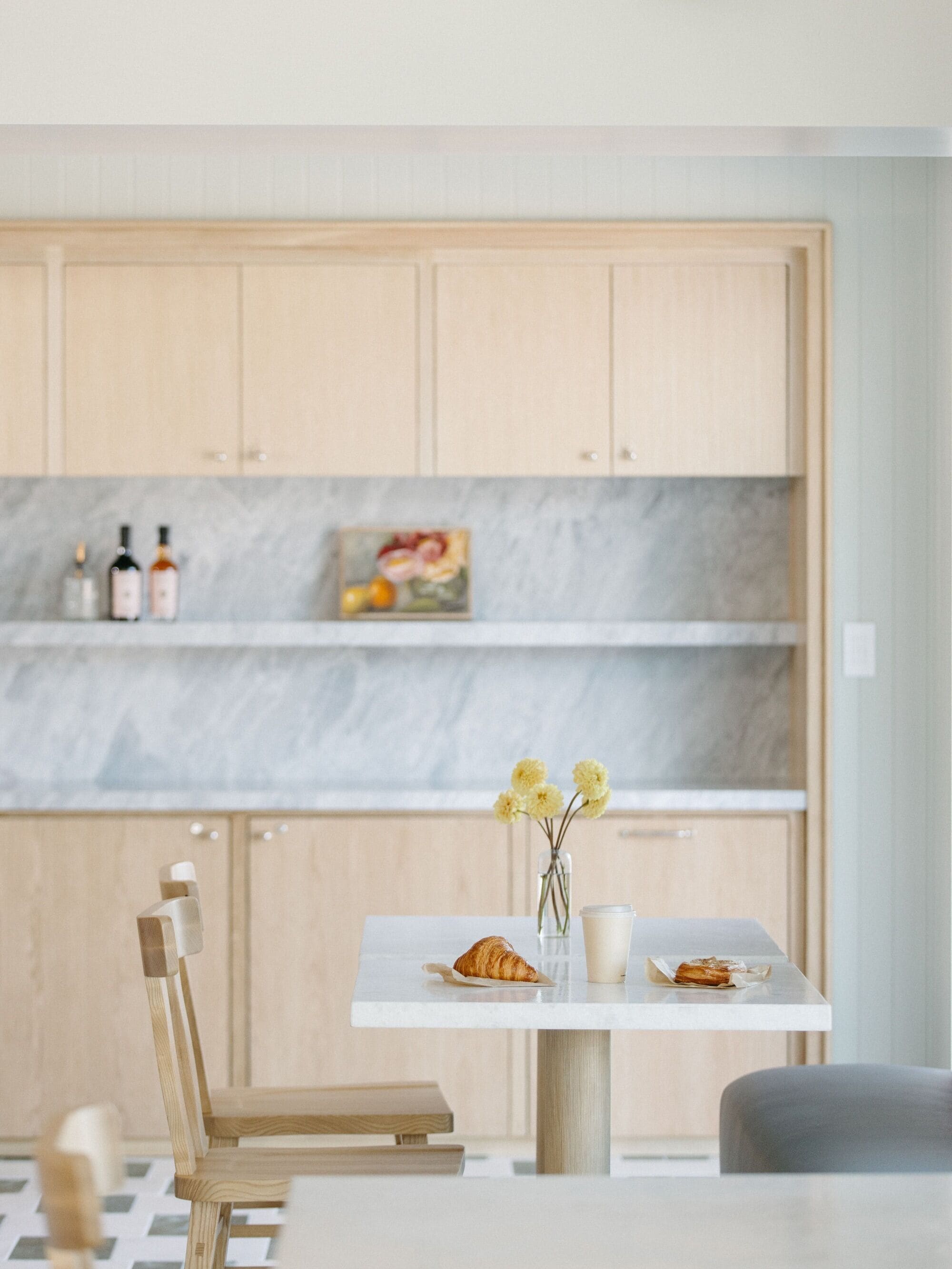 Eine moderne Küche mit Holzschränken, einer Marmor-Spritzschutzwand und einem Essbereich mit Tisch für zwei Personen.