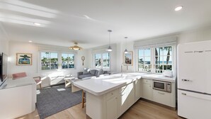 A modern kitchen with a large island, white cabinetry, and a view of palm trees.