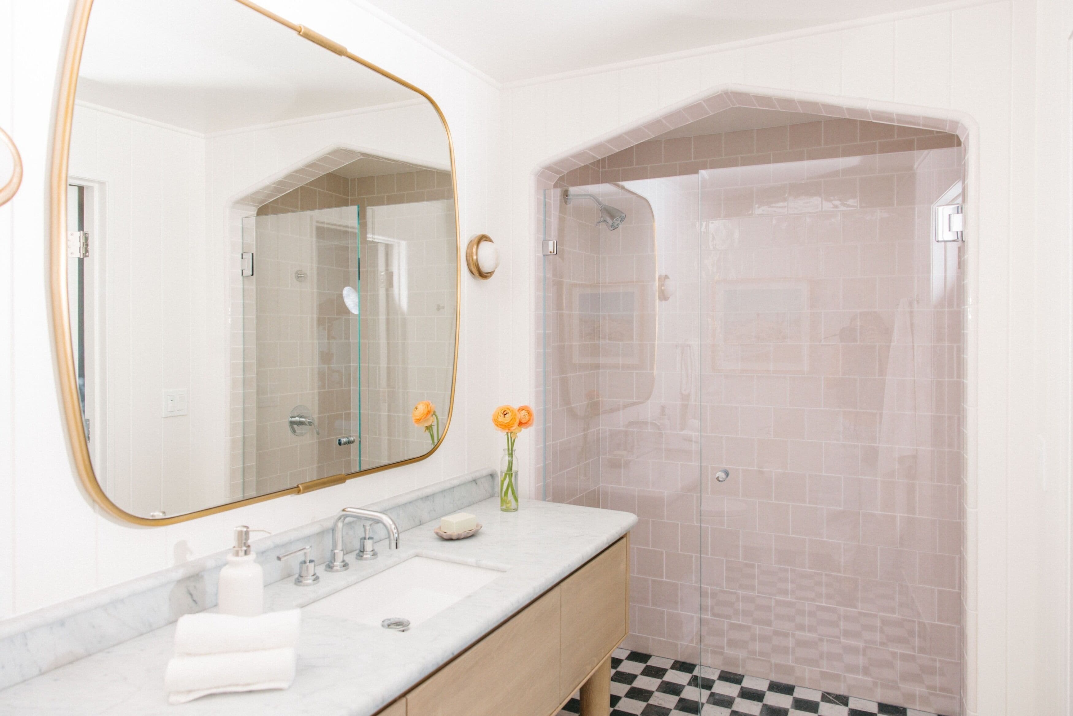 A bathroom with a marble sink, a large mirror, and a shower with a checkered floor.