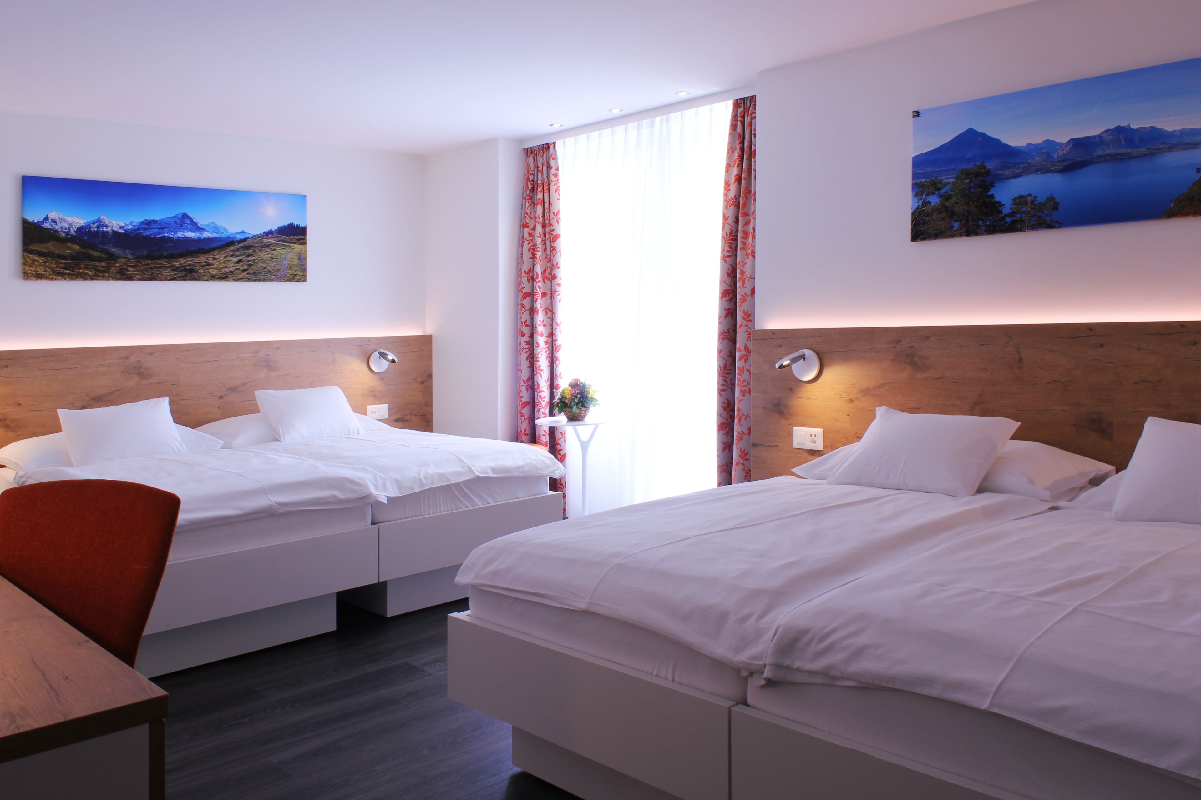 A hotel room with two beds, a wooden headboard, a desk, and a chair.