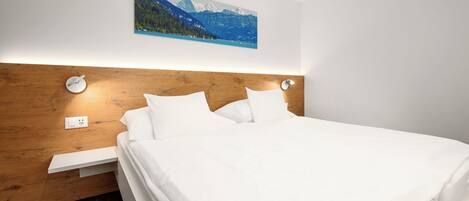 Cama bem arrumada com lençóis brancos, cabeceira de madeira e uma pintura de paisagem montanhosa acima.