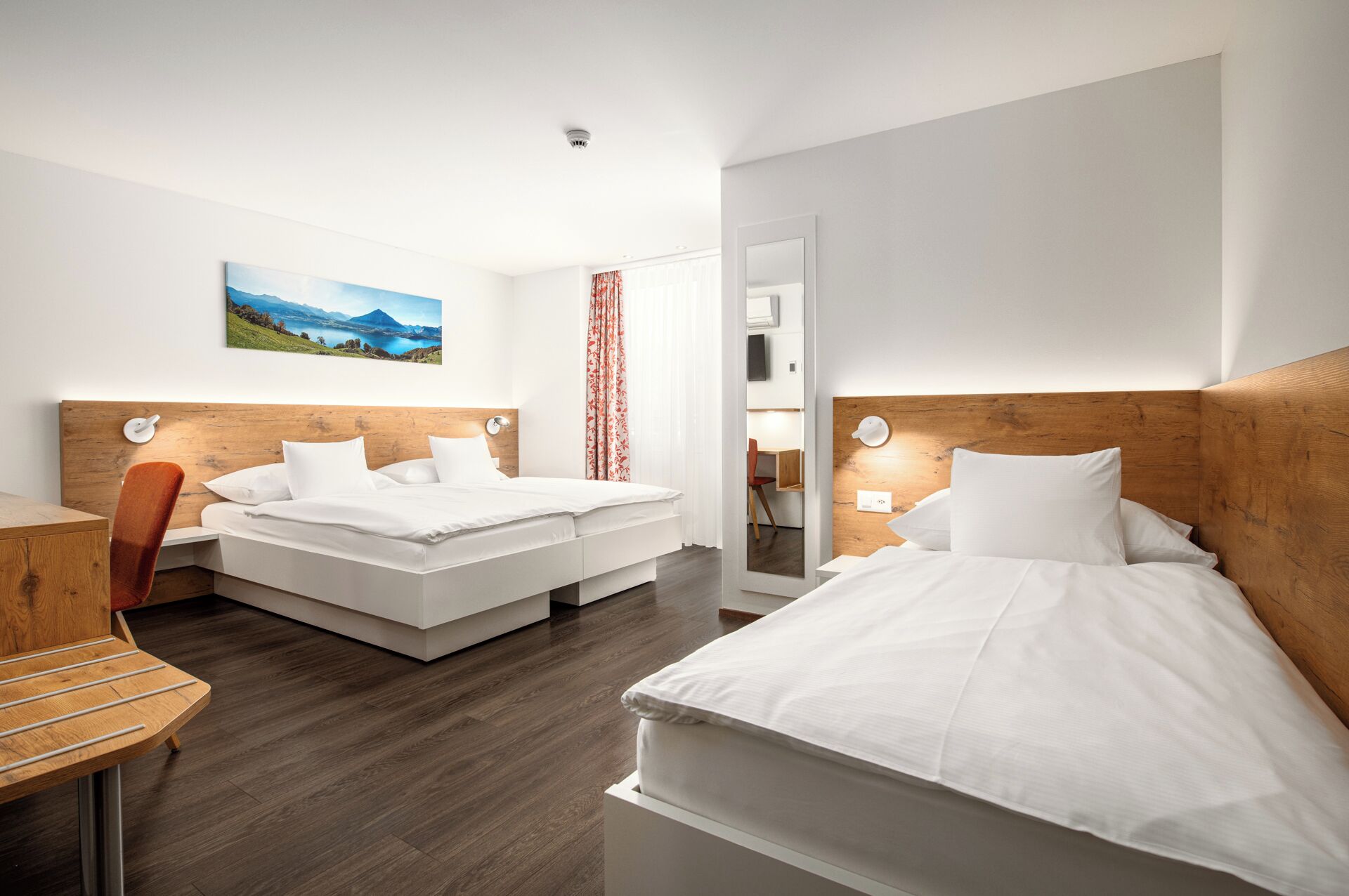 A hotel room with two beds, a desk, and a chair.