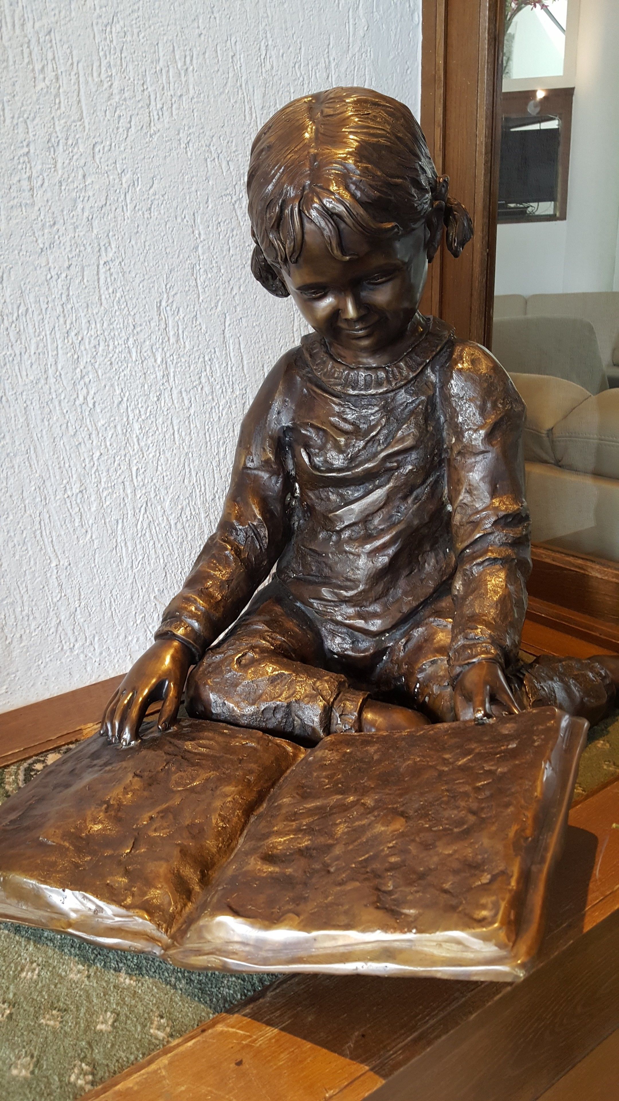 Una estatua de bronce de una figura sentada con un libro.