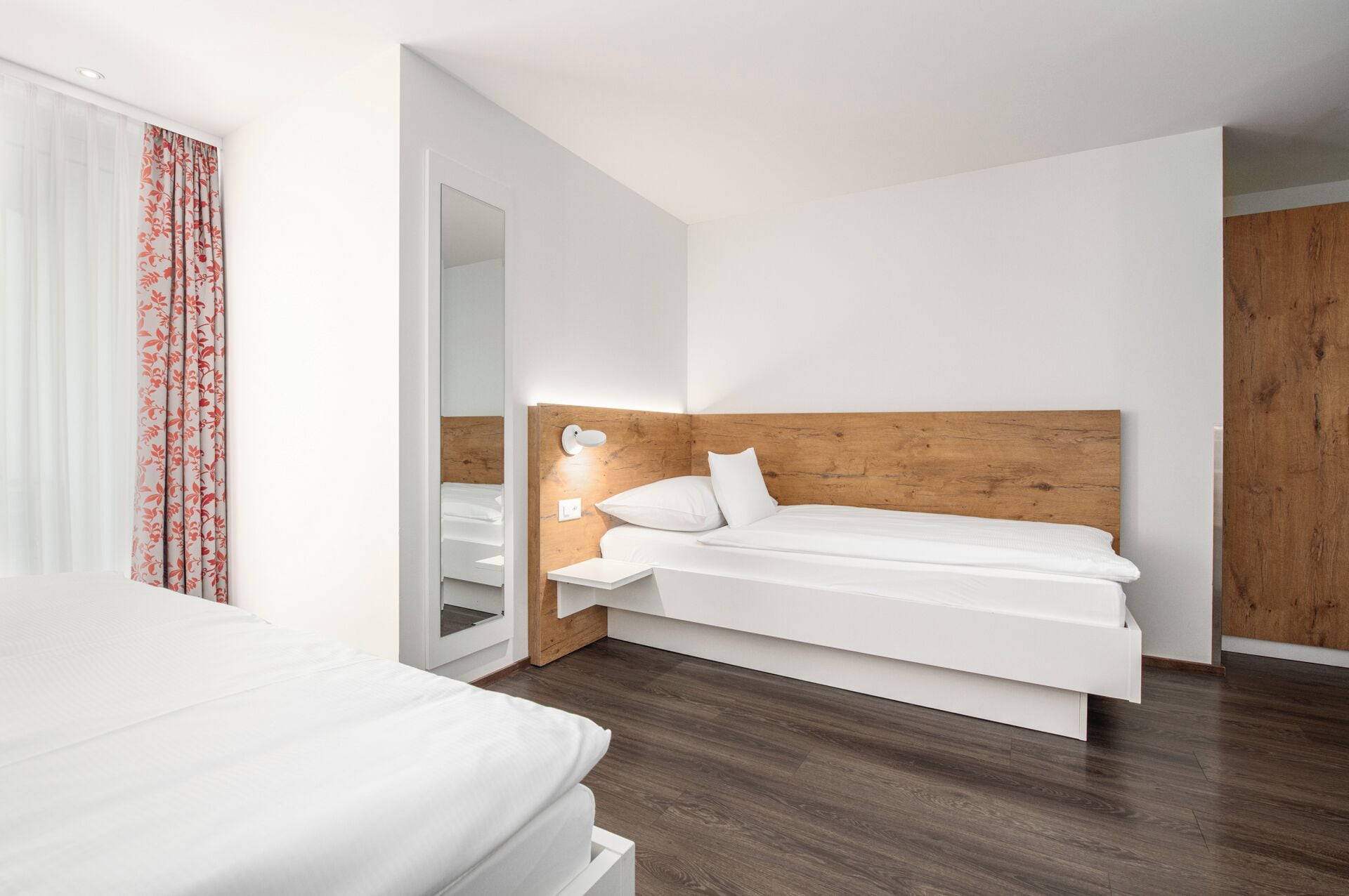 A modern bedroom with a wooden headboard, a white bed, and a nightstand.