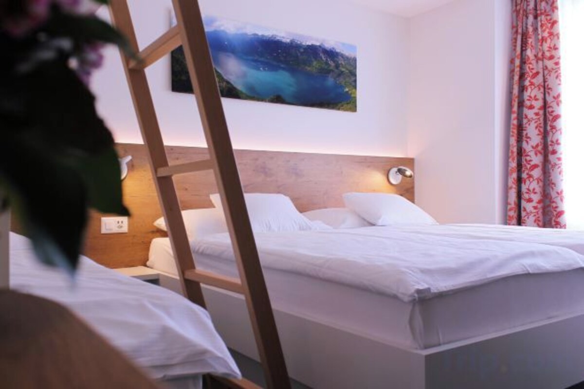 Una habitación de hotel con una cama, una mesita de noche, una lámpara de pared y un cuadro.