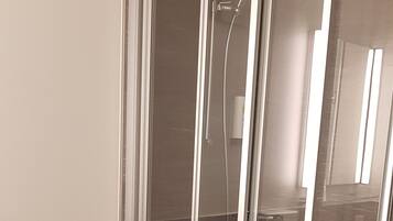 Un baño moderno con ducha envuelta en vidrio, inodoro y grifo de pared.