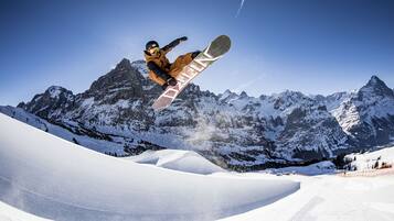 Ein Snowboarder vollführt einen Sprung vor einer Bergkulisse.
