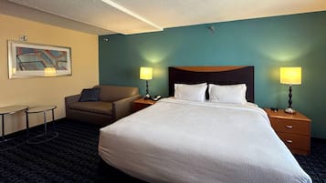 Una habitació d'hotel amb un llit gran, dues taules de nit amb làmpades, un sofà i una taula petita.