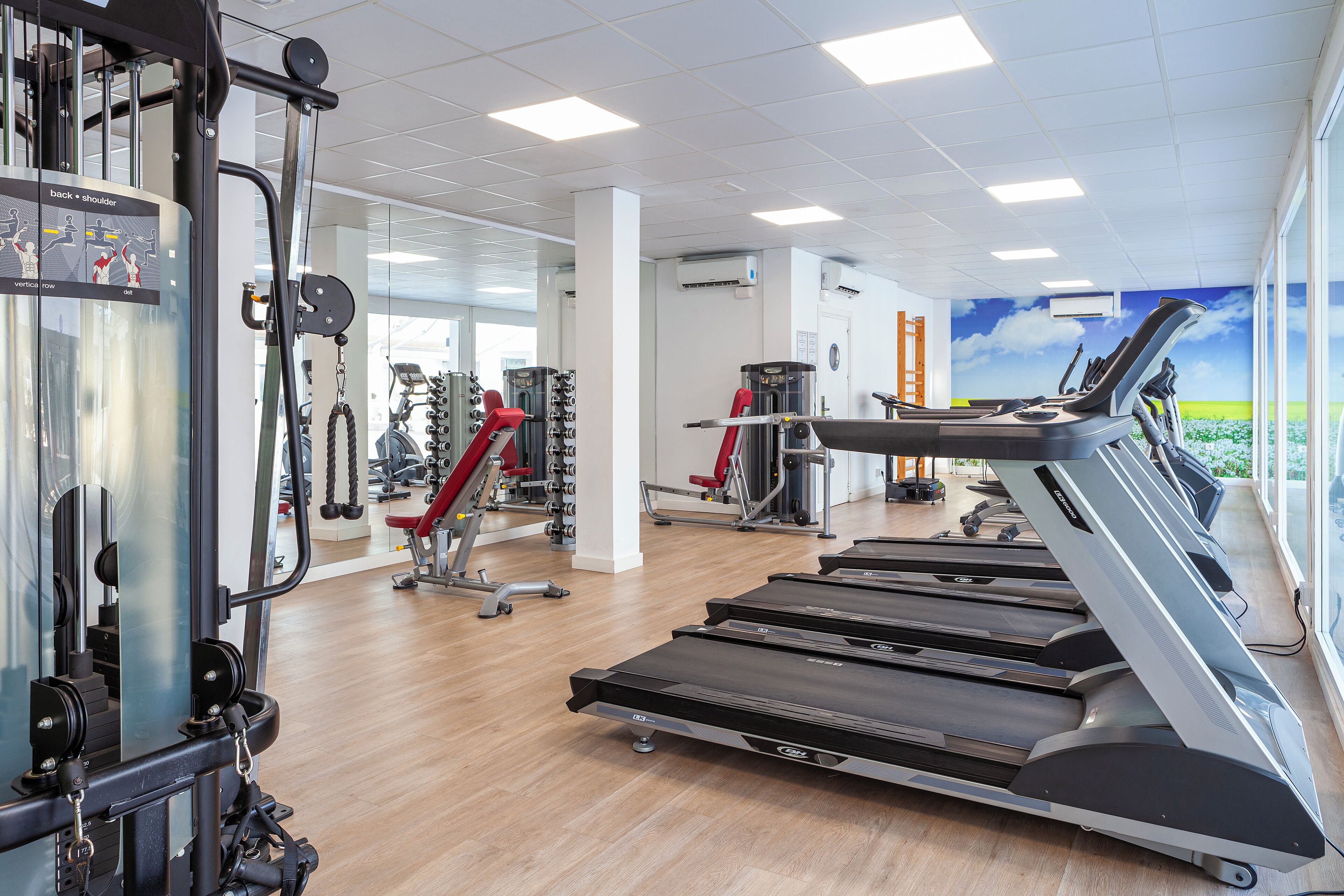 A gym with treadmills, weight machines, and mirrors.