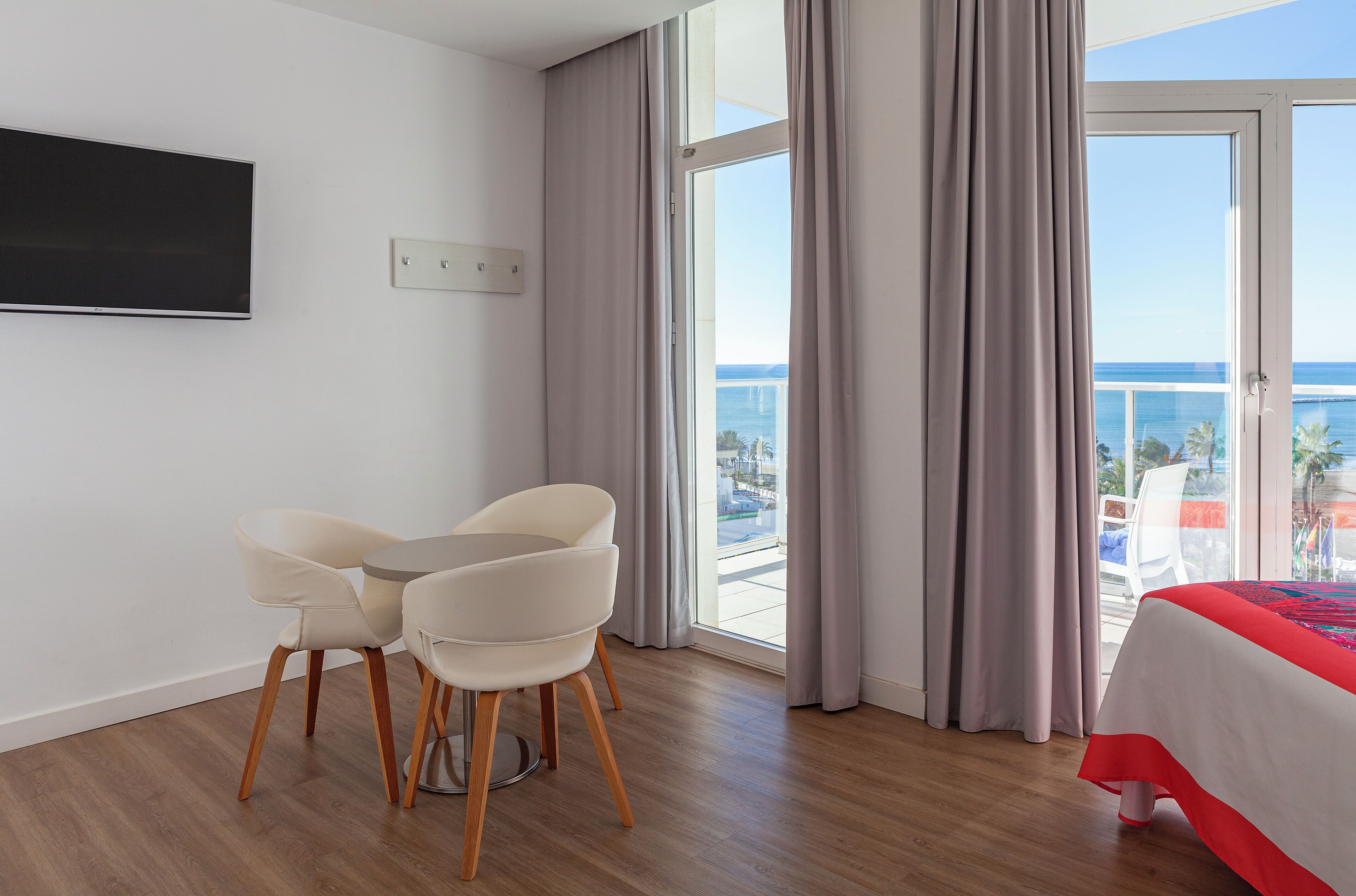 Hotellihuone, jossa on parveke, sänky, televisio ja kaksi tuolia.