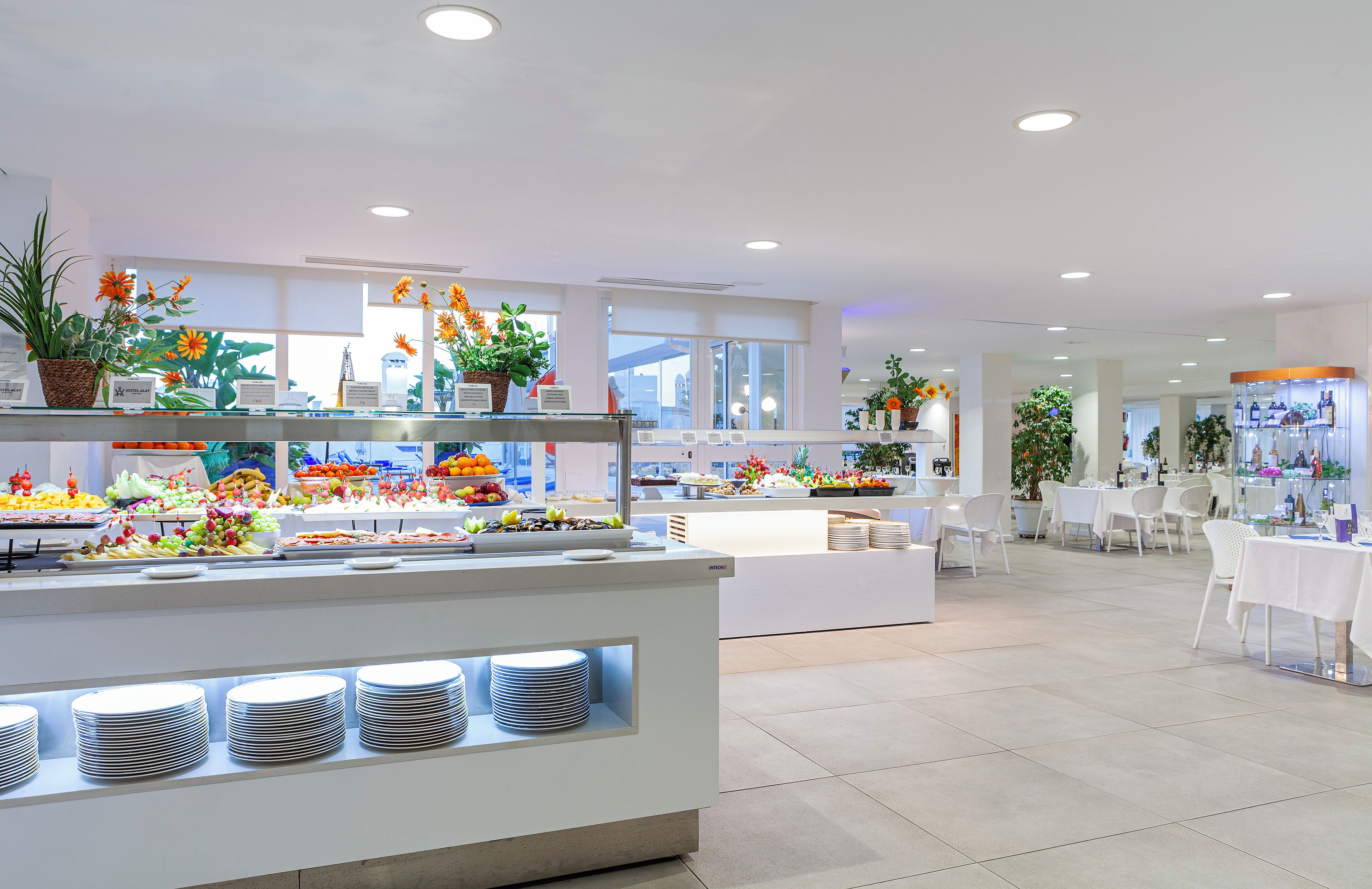 En modern hotellobby med ett område för buffé, vita möbler och stora fönster.