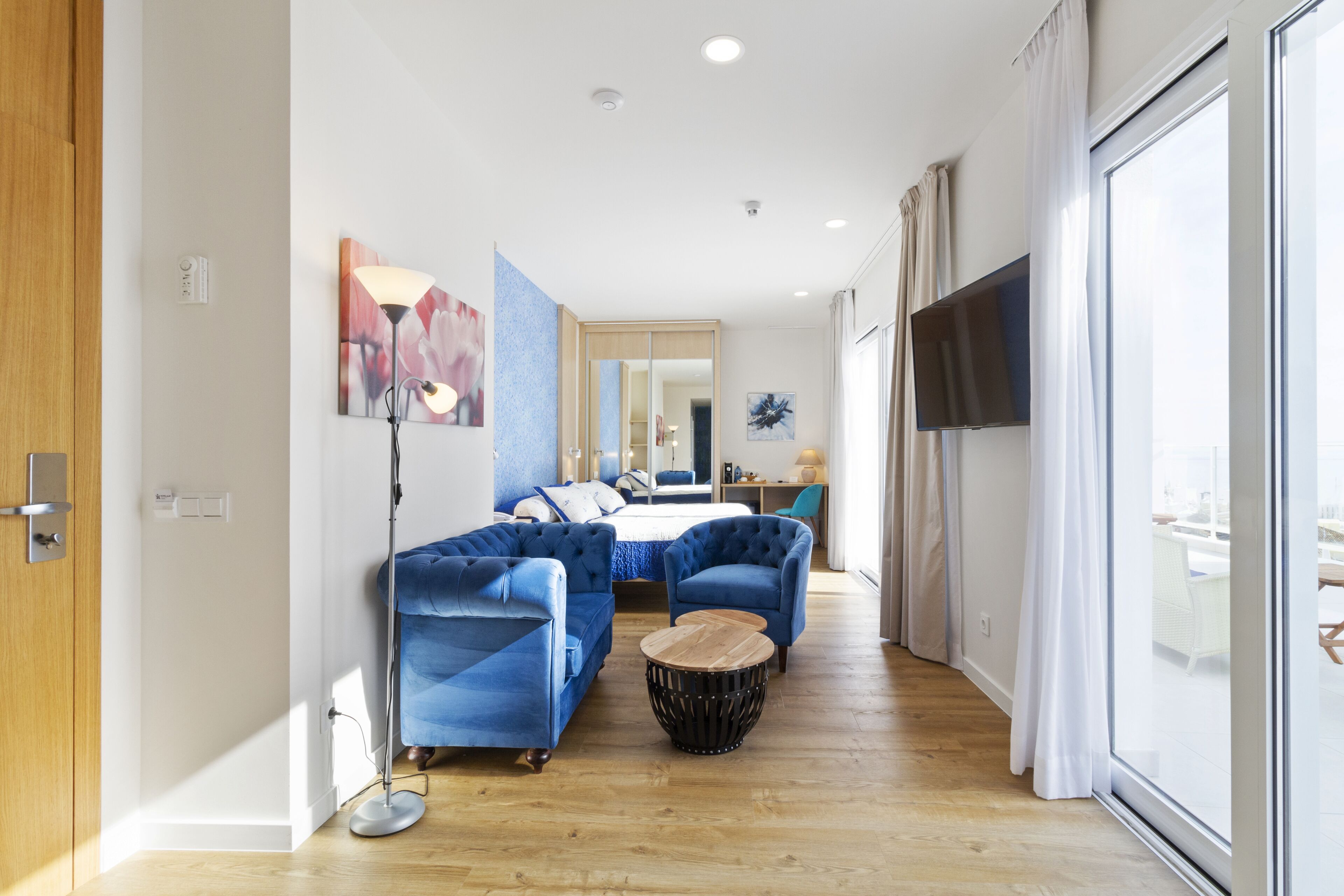 A modern living room with a sofa set, a coffee table, and a TV mounted on the wall.