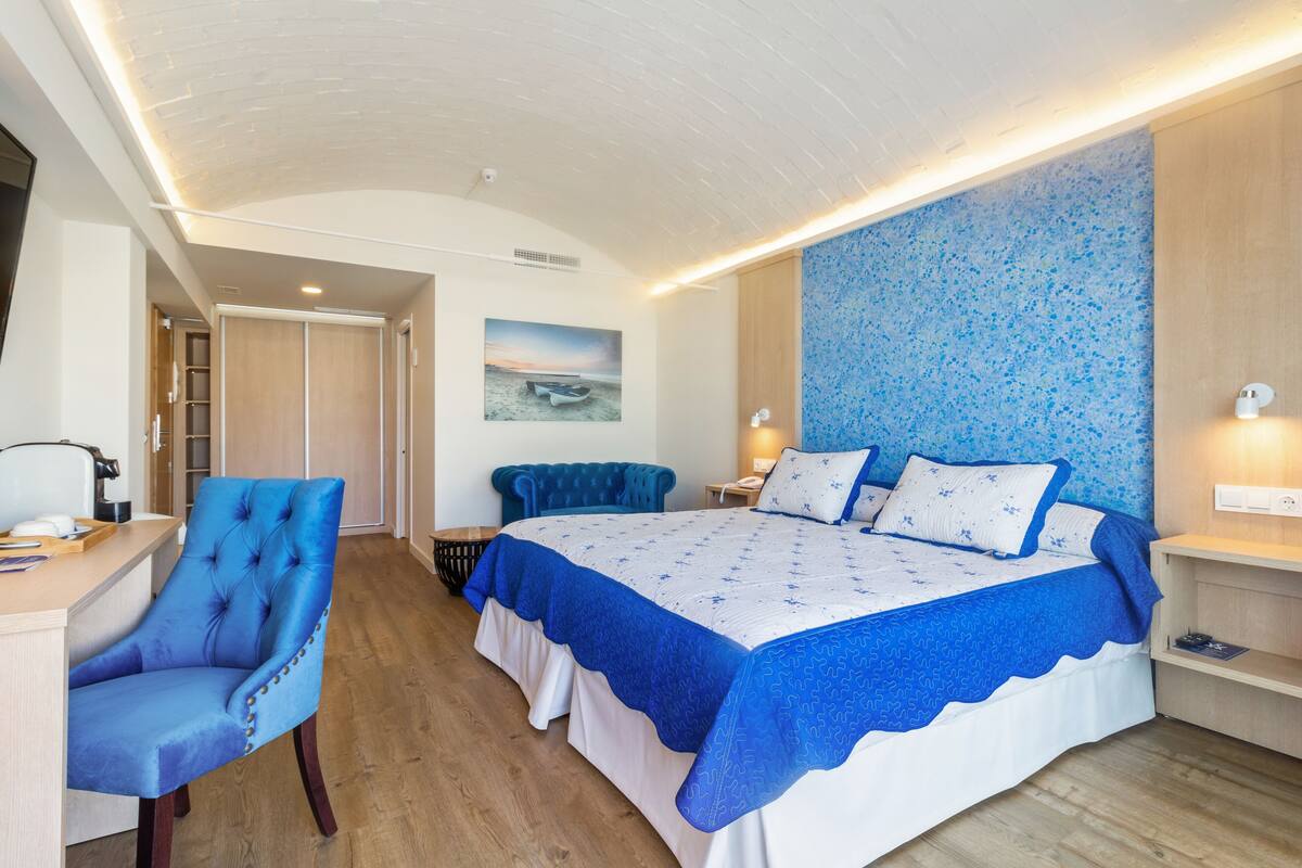 A bedroom with a large bed, a desk, and a chair.