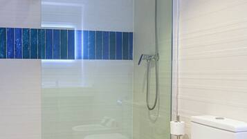 A modern bathroom with a glass-enclosed shower, a white toilet, and a blue-tiled shower area.