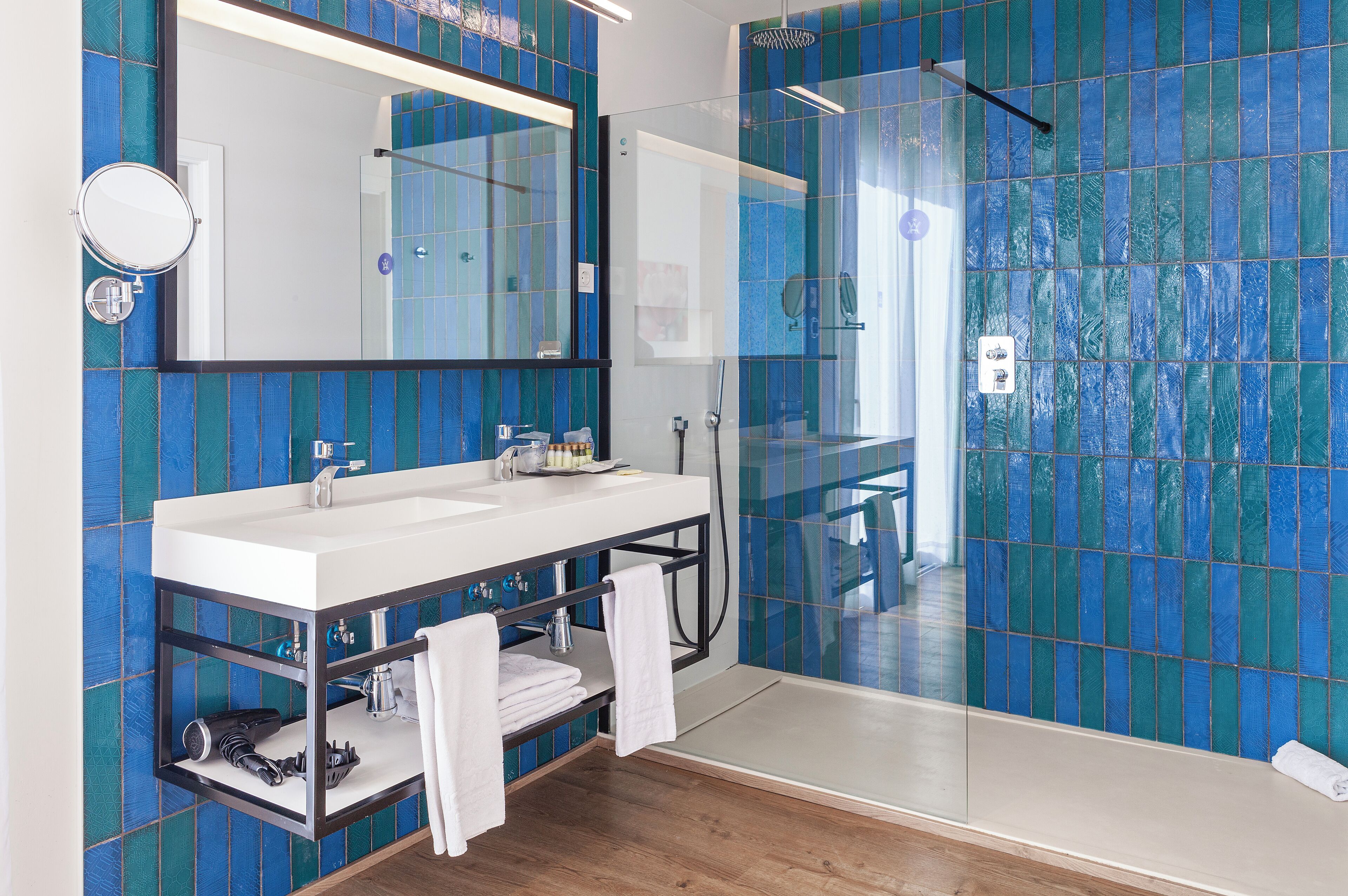 A modern bathroom with a glass-enclosed shower, a white sink with a black countertop, and a large mirror.