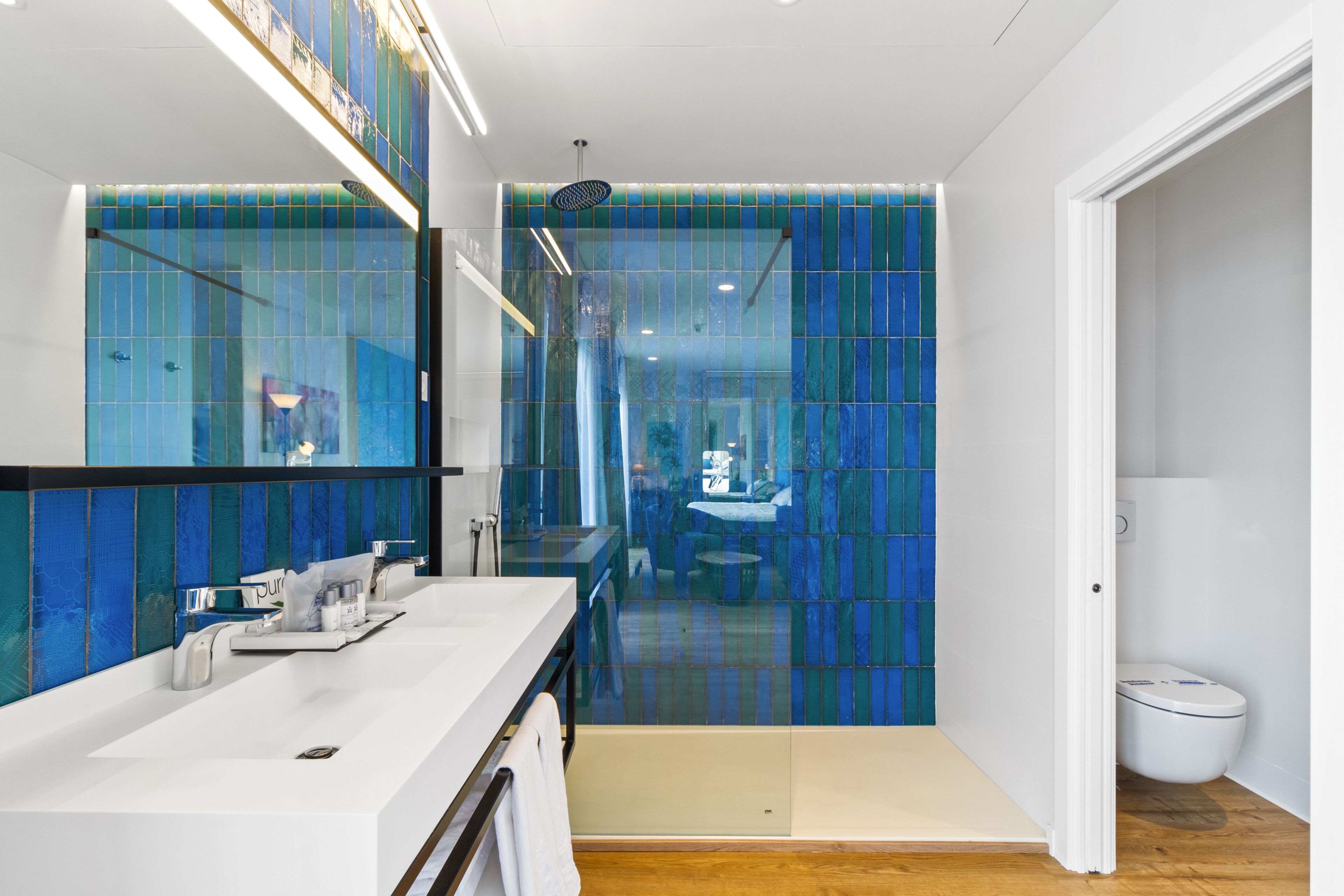 Une salle de bain moderne avec un lavabo blanc, un miroir et un espace douche.