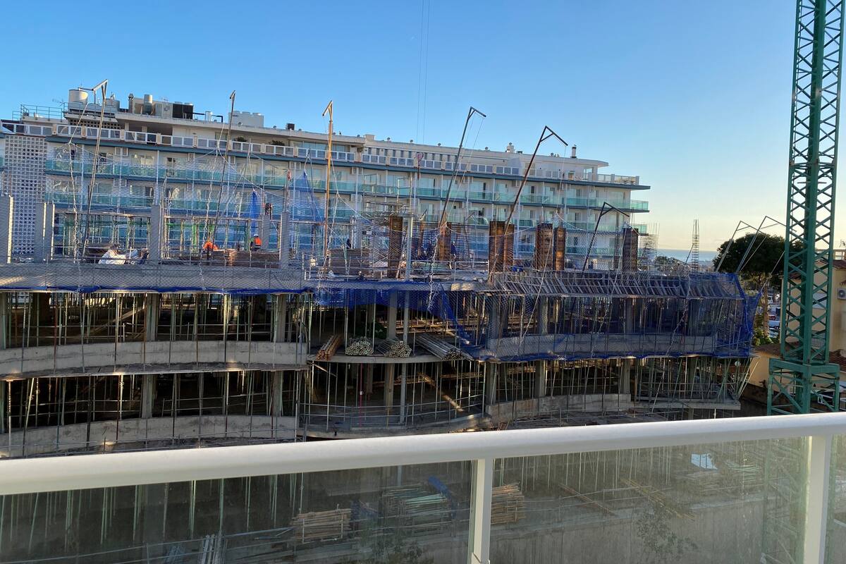 A multi-story building under construction with scaffolding and construction materials visible.
