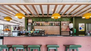 A bar area with a wooden ceiling, green stools, and a variety of bottles and glasses on shelves. - B&B Hotel Rothrist Olten (Rothrist)