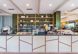 A breakfast bar with a variety of food items and a coffee machine.