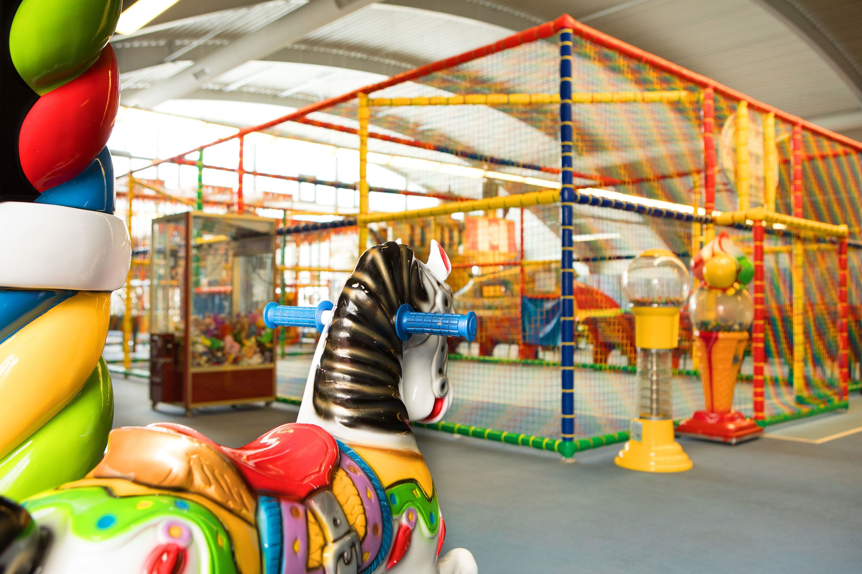 Un carrusel con caballos de colores y una jaula en el fondo.