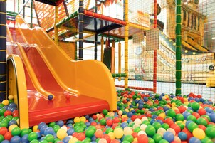 Zona de juegos con un tobogán y una piscina de pelotas, llena de bolas multicolores.