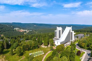 Un edificio moderno con un diseño arquitectónico único, rodeado de exuberante vegetación y un paisaje montañoso.