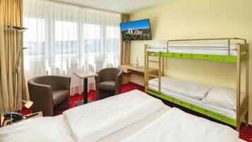 Ein Hotelzimmer mit zwei Betten, einem Fernseher, einem Schreibtisch und zwei Sesseln.