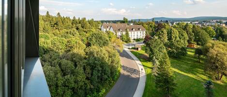 A curved road leading to a large building surrounded by dense trees and greenery.