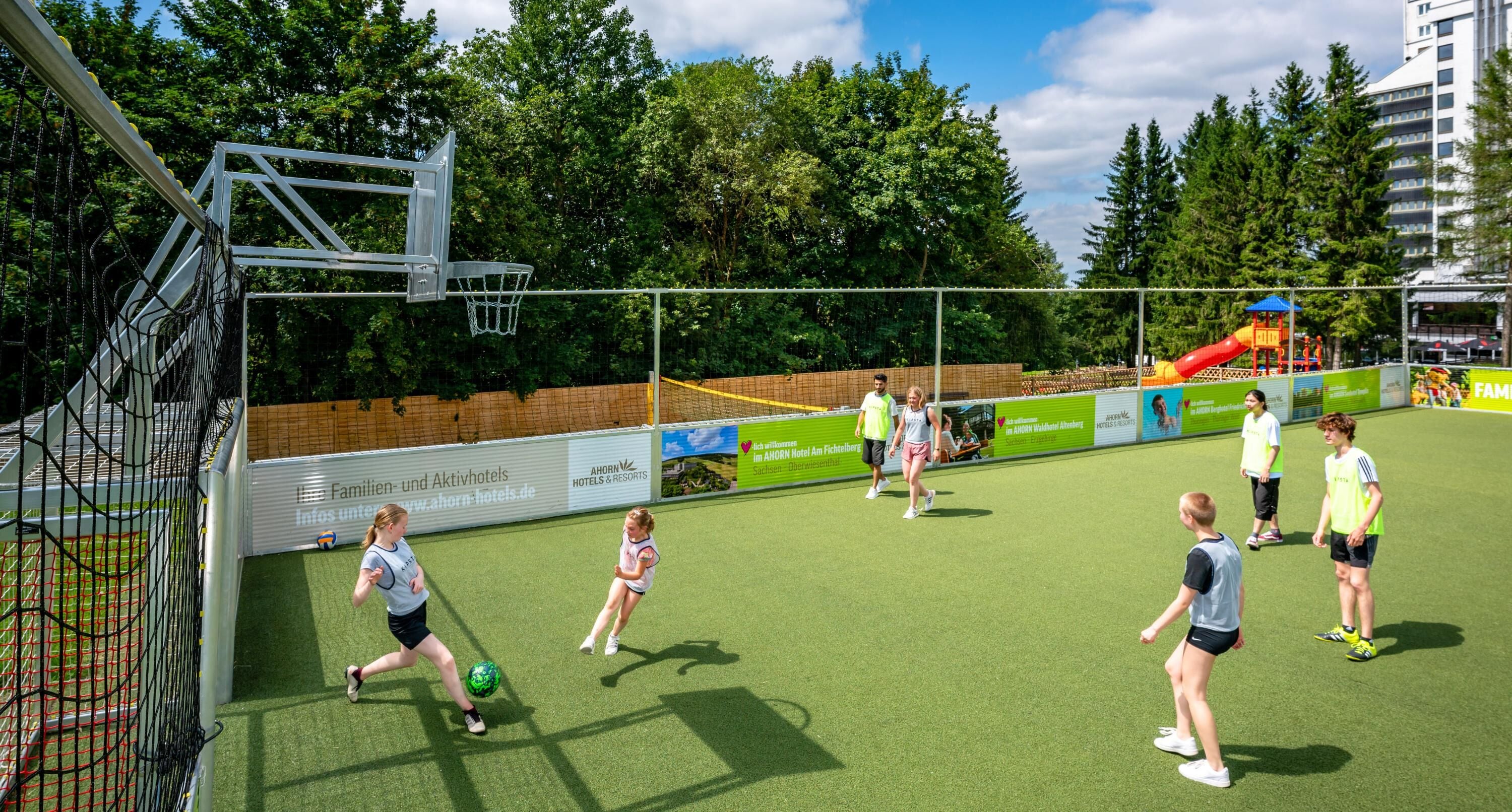 A sports field with a goalpost, a net, and a slide in the background.