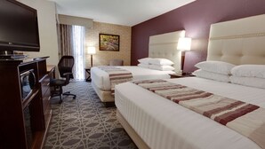 A hotel room with two beds, a desk with a television, a chair, and a patterned carpet. - Drury Inn & Suites San Antonio Northeast (San Antonio)