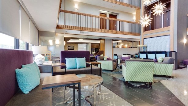 A spacious lobby with a high ceiling, multiple seating areas, and a central staircase. - Drury Inn & Suites San Antonio Northeast (San Antonio)