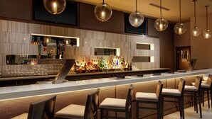 A bar area with a long counter, multiple stools, and hanging spherical light fixtures. - Embassy Suites by Hilton Crystal City National Airport (Arlington)