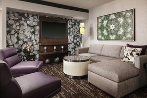 Una sala de estar moderna con un sofá modular, un televisor de pantalla plana, decoración en la pared y una alfombra estampada.