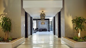 A modern hallway with a reflective floor, a central seating area with a sofa and chairs, and a unique striped pendant light. - Embassy Suites by Hilton Crystal City National Airport (Arlington)