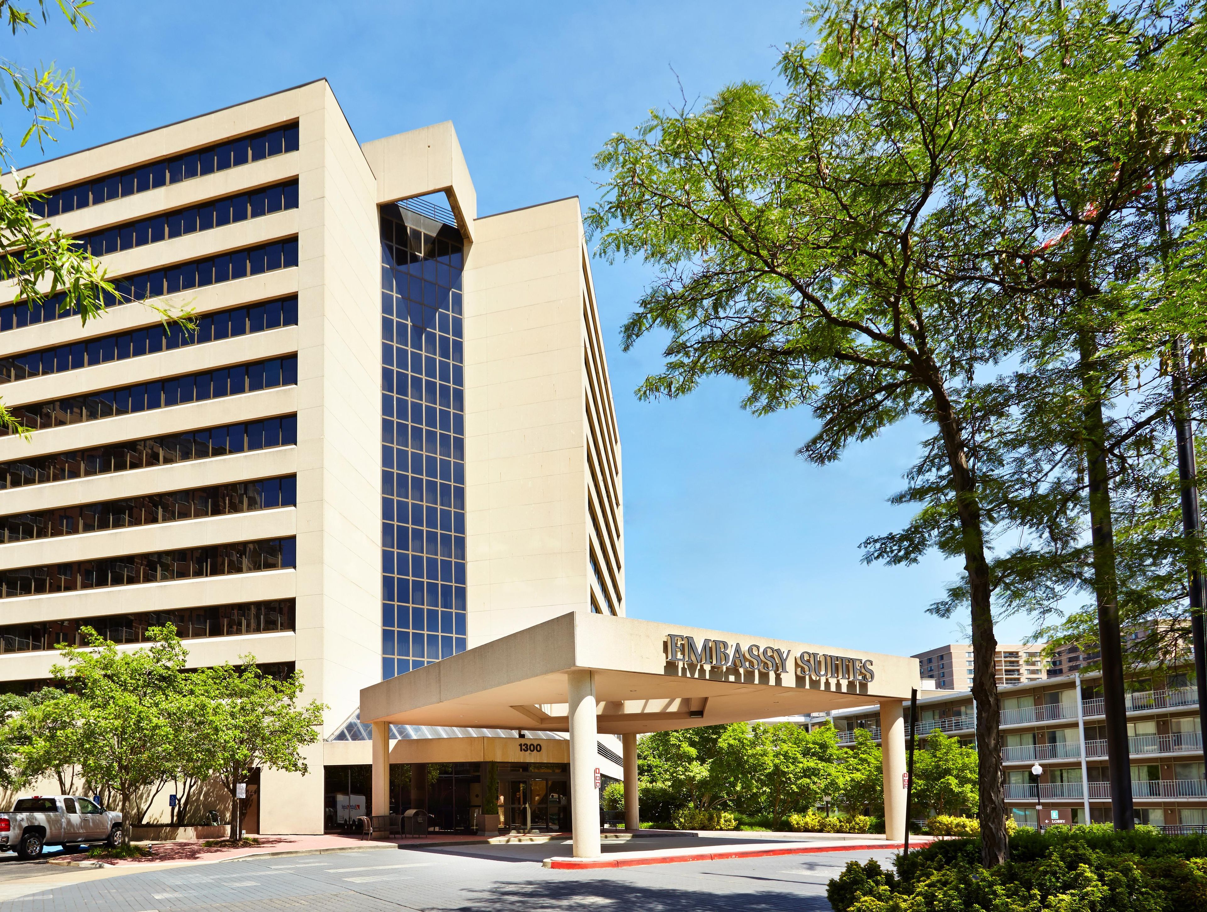 L’entrée d’un hôtel, avec un espace abrité portant l’inscription « Embassy Suites » et un parking.
