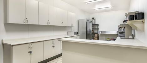 A modern kitchen with white cabinetry, a stainless steel refrigerator, and a built-in oven.