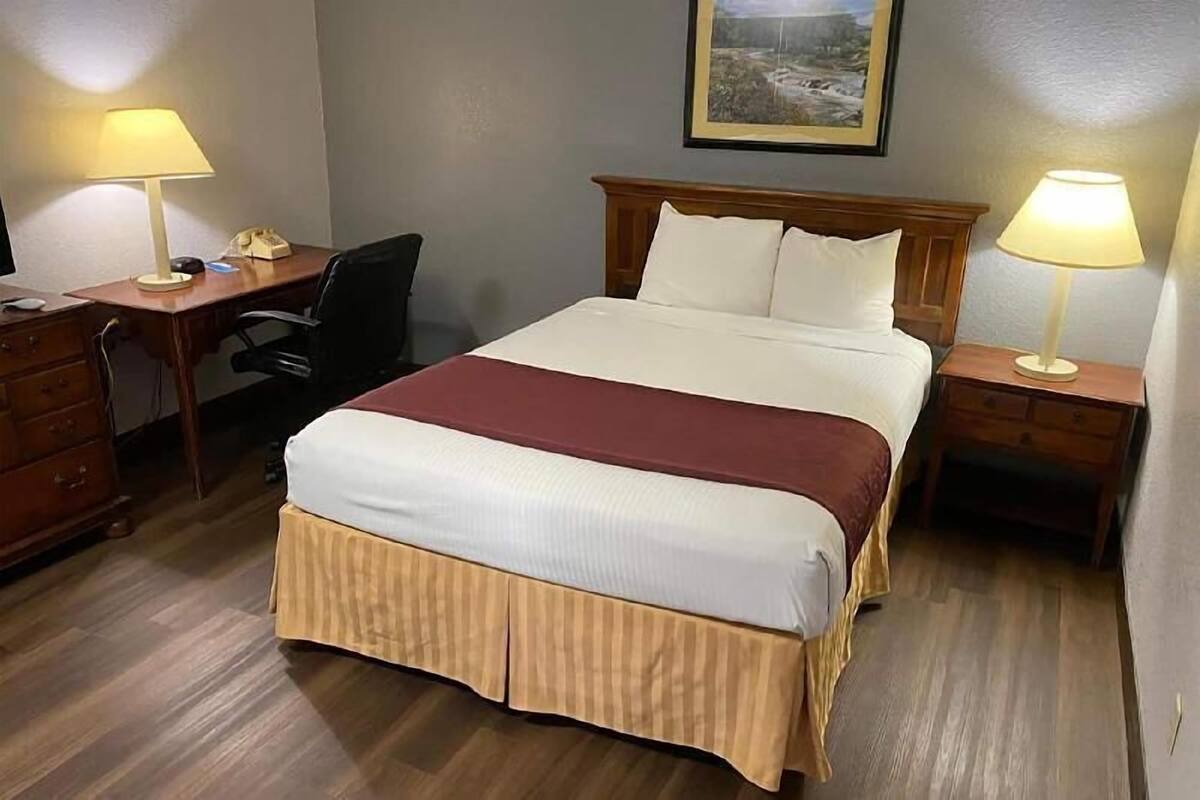 A hotel room with a bed, desk, chair, and nightstands.