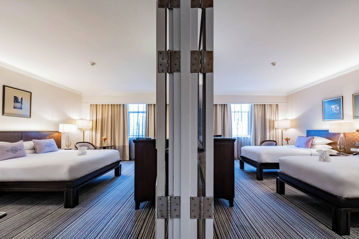 A hotel room with two beds, a large mirror, a desk, and a chair.