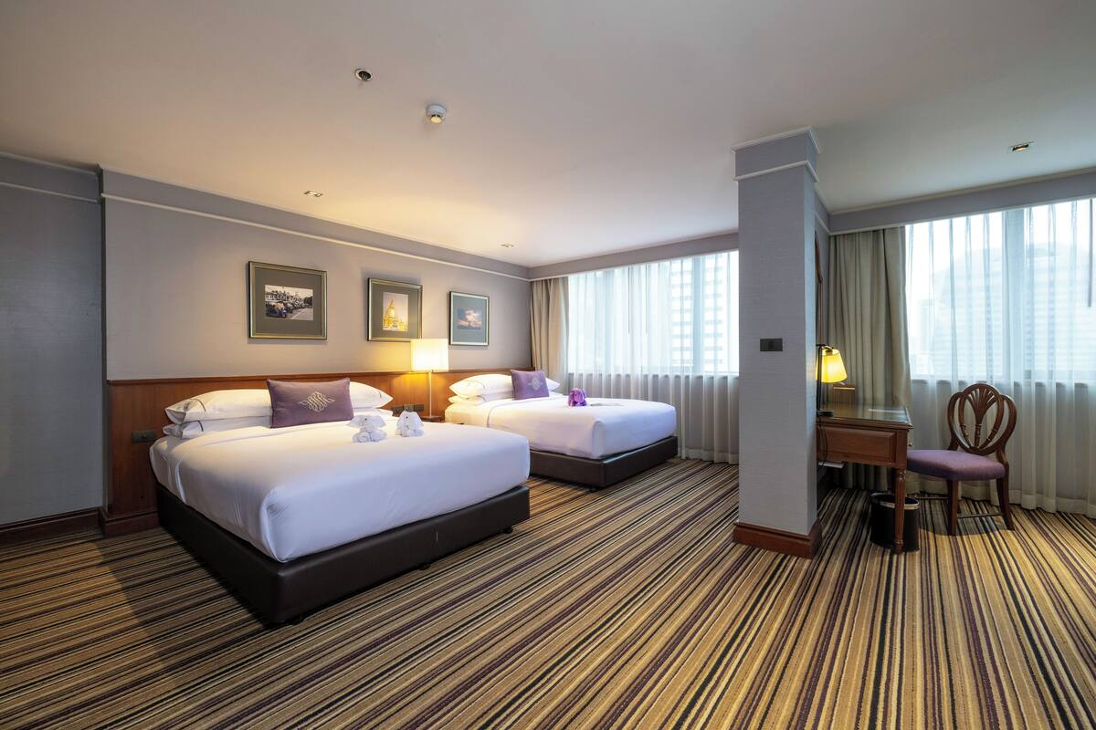 A hotel room with two beds, a desk, and a chair.