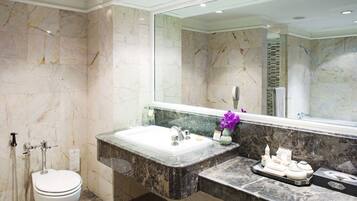 A bathroom with a marble sink, a toilet, and a large mirror.