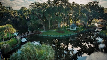 Un belvédère entouré d’un étang, d’arbres et d’un pont.