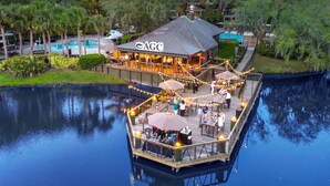 A waterfront restaurant with a deck, outdoor seating, and a pool in the background. - Sawgrass Marriott Golf Resort & Spa (Ponte Vedra Beach)