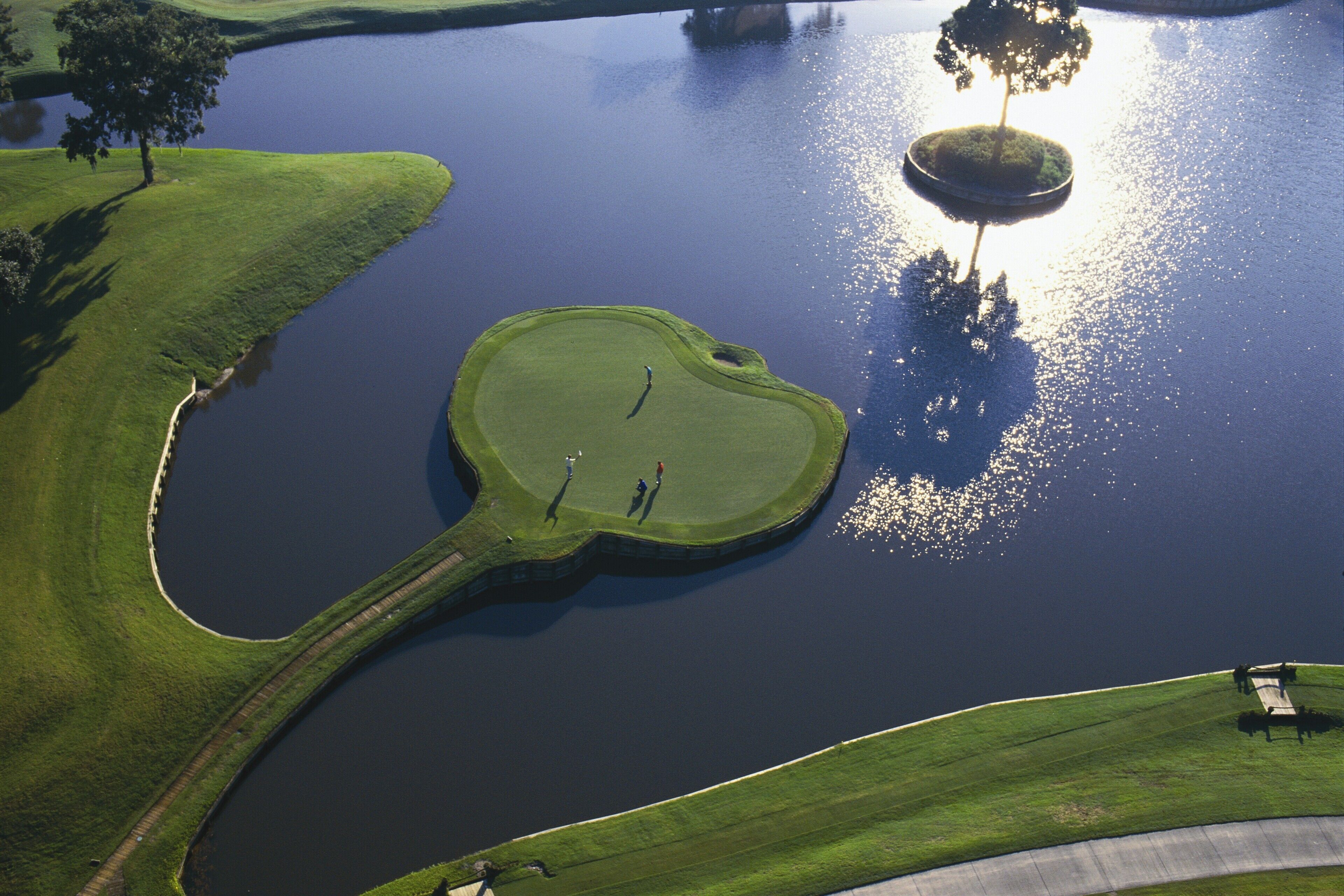 An aerial view of a golf course with a pond, surrounded by green grass and trees.